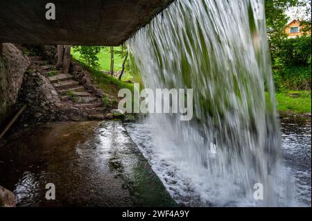 Passage unter einem künstlichen Wasserfall. Wasserwand, fallende Kaskade. Vecais Parks, Smiltene, Lettland. Stockfoto