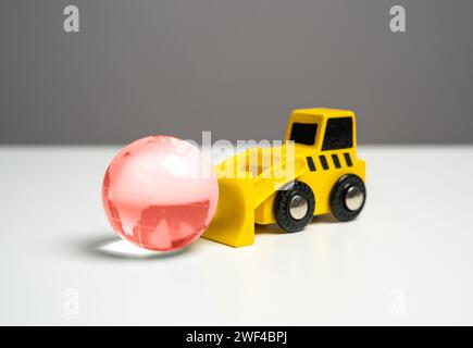 Ein Bulldozer und ein roter Globus symbolisieren eine Welt in Krise. Schlechte Ökologie. Die Auswirkungen des Menschen auf die Umwelt, die zu Überlegungen über ökologische Belange anregen a Stockfoto