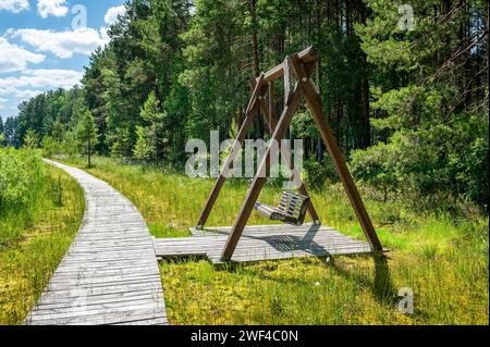 Schaukelsitz am Holzpier-Ponton auf dem See. Holzstege, sumpfiges Seeufer. Bilska-See, Lettland. Stockfoto