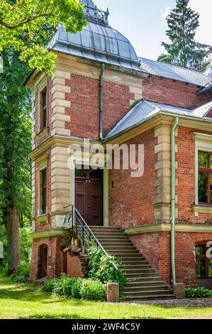 Das Herrenhaus Aumeisteru wurde im neogotischen Stil erbaut. Malerische Kulisse eines Innenhofs mit interessantem Eingangsbereich. Lettland, Baltikum. Stockfoto