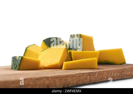 Nahaufnahme von Kürbisscheiben auf einem hölzernen Schneidebrett, geschnittenen und Gemüsestücken beim Kochen auf dem Küchentisch, selektiv fokussiert Stockfoto