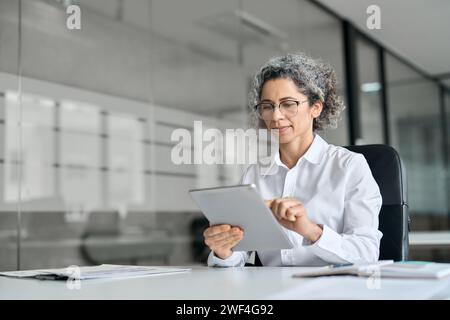 Geschäftige, reife Geschäftsfrau, die im Büro einen Tablet-Computer verwendet. Stockfoto