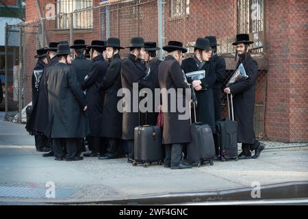 Eine Gruppe orthodoxer jüdischer Männer wartet auf einen Bus, der sie zu den Klassen auf der anderen Seite von Brooklyn bringt. In Williamsburg. Stockfoto