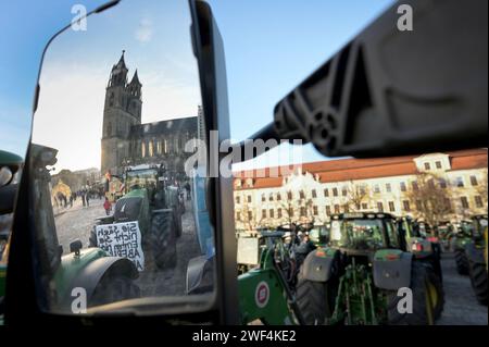 Magdeburg, Deutschland. Januar 2024. Die Kathedrale spiegelt sich in einem Traktorspiegel wider und andere Fahrzeuge parken auf dem Domplatz für die Bauernkundgebung. Unter dem Motto "zu viel ist zu viel" protestierten Hunderte von Bauern und Forstwirten aus mehreren bundesländern gegen die Haushaltspolitik der Bundesregierung. Quelle: Heiko Rebsch/dpa/Alamy Live News Stockfoto