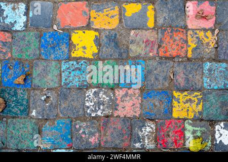 Foto eines lebendigen Streetart-Stücks mit gemalten Kopfsteinpflastersteinen in verschiedenen Farben, die eine verspielte Note auf urbanen Oberflächen bieten. Stockfoto