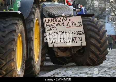 Magdeburg, Deutschland. Januar 2024. Ein Protestplakat mit der Aufschrift „Bauern ernähren alle, sogar die Gegner, die sie haben!“ Ist an einem Traktor befestigt. Unter dem Motto "zu viel ist zu viel" protestierten Hunderte von Bauern und Forstwirten aus mehreren bundesländern gegen die Haushaltspolitik der Bundesregierung. Quelle: Heiko Rebsch/dpa/Alamy Live News Stockfoto