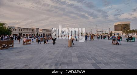 Souq Waqif Doha, Qatar Hauptstraße Sonnenuntergang, zeigt Einheimische und Besucher, die mit der Skyline von Doha im Hintergrund spazieren gehen Stockfoto