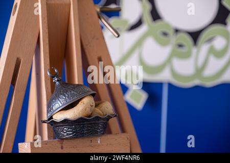 EID-Süßigkeiten mit Leinwand-Halter auf blauem Hintergrund mit arabischer Kalligraphie Stockfoto