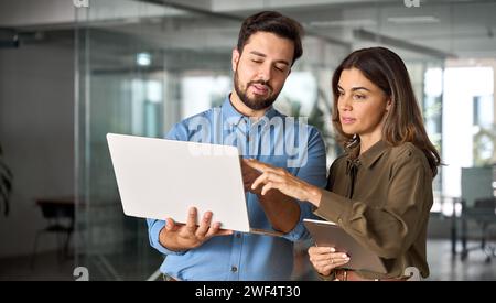 Geschäftlich beschäftigte Geschäftsleute, die im Büro mit Laptop arbeiten und sich unterhalten. Stockfoto