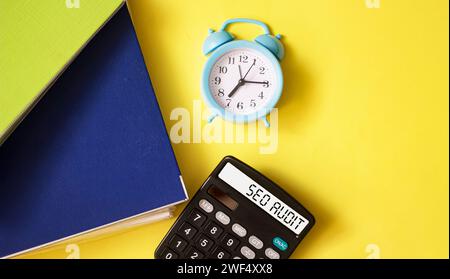 Geschäfts- und Finanzkonzept. Auf dem Tisch befinden sich eine Uhr und ein Taschenrechner mit der Aufschrift SEO AUDIT auf gelbem Hintergrund Stockfoto