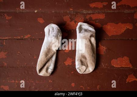 Dreckige weiße, kurze Socken, dreckige Sachen liegen auf einem alten Holzboden Stockfoto