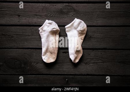Schmutzige weiße Socken liegen auf einem schwarzen Brett, schmutzige Sachen Stockfoto