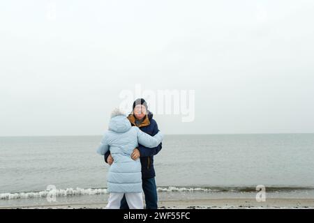 Ein älteres Paar hat Spaß und tanzt im Winter am Strand am Meer. Urlaub auf dem Meer. Stockfoto
