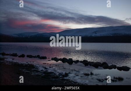 Ein abendlicher Blick auf Loch Morlich und die Cairngorm Mountains im Winter, Cairngorm National Park. Stockfoto