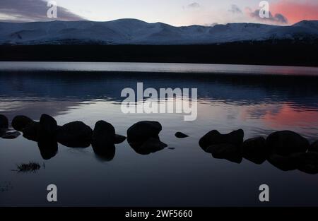 Ein abendlicher Blick auf Loch Morlich und die Cairngorm Mountains im Winter, Cairngorm National Park. Stockfoto