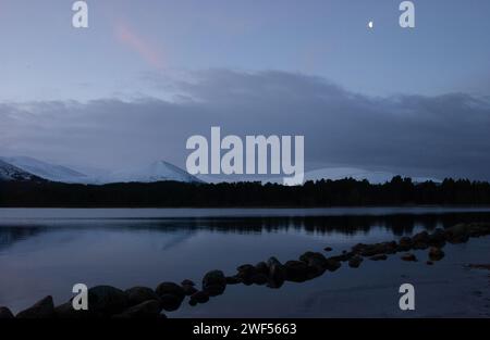 Ein abendlicher Blick auf Loch Morlich und die Cairngorm Mountains im Winter, Cairngorm National Park. Stockfoto