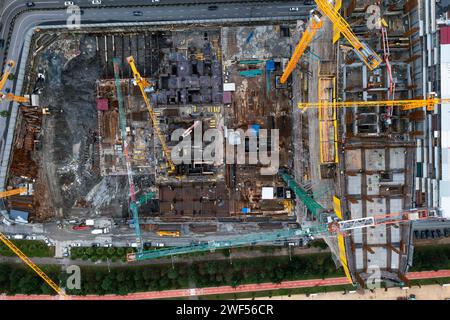 Von oben nach unten auf die Baustelle mit Turmkränen, die arbeiten und ein neues Appartementhaus in einem Wolkenkratzer bauen. Bauindustrie Stockfoto