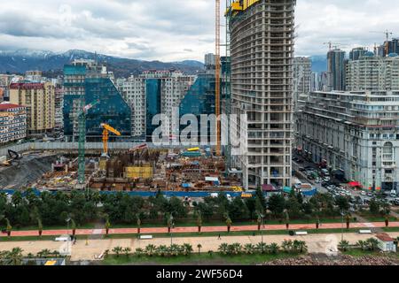 Aus der Vogelperspektive auf die Baustelle mit Turmkränen, die arbeiten und ein neues mehrstöckiges Appartementhaus bauen. Stadtentwicklung. Bauindustrie Stockfoto