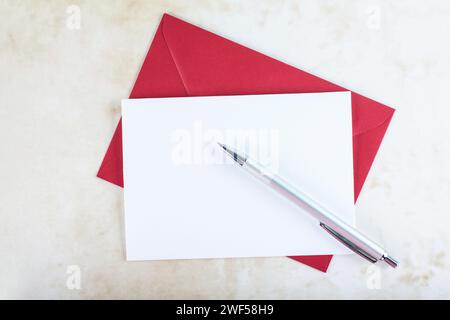 Roter Umschlag, leerer Einladungswagen und Stift. Stockfoto