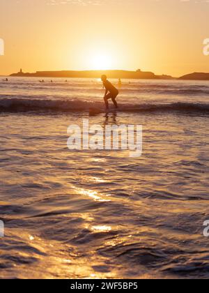 Surferin im Wasser bei Sonnenuntergang in Essaouira, Marokko, 28. Januar 2024 Stockfoto