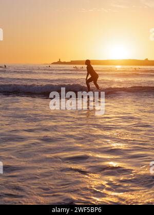 Surferin im Wasser bei Sonnenuntergang in Essaouira, Marokko, 28. Januar 2024 Stockfoto