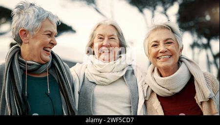 Reden, lachen und alte Freundinnen im Park zusammen, um sich im Ruhestand zu binden. Glücklich, lächelnd und lustig mit einer Gruppe von Senioren Stockfoto