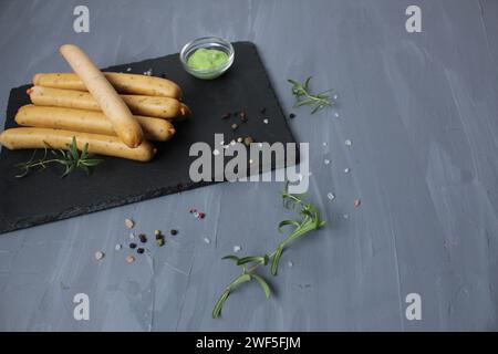 Hähnchenwürste zum Braten liegen auf einem Brett auf einem grauen Hintergrund mit Platz für eine Kopie Rezept. Hühnerfleischprodukte. Proteinnahrung. Stockfoto