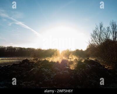 Malden, Niederlande. Januar 2024. Abfallende organische Stoffe, die auf einem Feld platziert werden, erzeugen aufgrund der Gefriertemperaturen Dampf. Nachdem drei benannte Stürme (Sturm Henk, Sturm Jocelyn und Sturm Isha) im Januar durch die Niederlande gezogen wurden, haben an diesem Wochenende die eisigen Temperaturen in der Nacht die Landschaft in weiße Landschaften verwandelt. Am Sonntagmorgen genossen Wanderer und Biker bei ihren Outdoor-Sportarten sonnige und kalte Temperaturen. (Foto: Ana Fernandez/SOPA Images/SIPA USA) Credit: SIPA USA/Alamy Live News Stockfoto