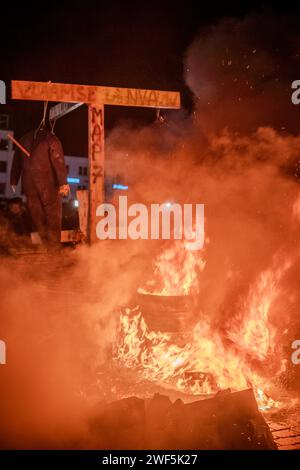 Turnhout, Antwerpen, Belgien, 28. Januar 2024, dieses Bild ist eine Nahaufnahme der turbulenten Flamme des Protests der Landwirte in Turnhout, Belgien, gegen das Stickstoffabkommen. Das Feuer dominiert den Rahmen, mit seinen wilden Zungen aus Flammen, die in einem Tanz des Trotzes ausbreiten und ein fast abstraktes Muster aus Licht und Energie erzeugen. Der intensive orange Farbton sättigt die Szene, unterbrochen von der Straßenlaterne, die durch den rauchigen Dunst im Hintergrund dringt, was auf die urbane Umgebung des Protestes hindeutet. Die Kopfsteinpflasterstraße unter den Flammen deutet auf die historische und traditionelle Kulisse hin Stockfoto