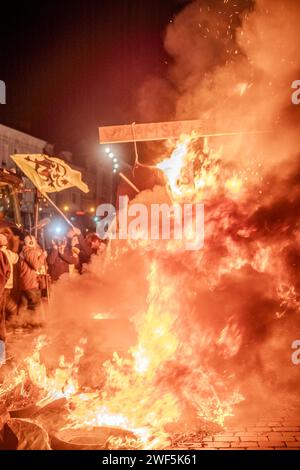 Turnhout, Antwerpen, Belgien, 28. Januar 2024, dieses Bild ist eine Nahaufnahme der turbulenten Flamme des Protests der Landwirte in Turnhout, Belgien, gegen das Stickstoffabkommen. Das Feuer dominiert den Rahmen, mit seinen wilden Zungen aus Flammen, die in einem Tanz des Trotzes ausbreiten und ein fast abstraktes Muster aus Licht und Energie erzeugen. Der intensive orange Farbton sättigt die Szene, unterbrochen von der Straßenlaterne, die durch den rauchigen Dunst im Hintergrund dringt, was auf die urbane Umgebung des Protestes hindeutet. Die Kopfsteinpflasterstraße unter den Flammen deutet auf die historische und traditionelle Kulisse hin Stockfoto