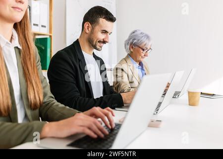 Drei hispanische Geschäftsleute arbeiten in einem hellen Büro an einem Laptop. Stockfoto