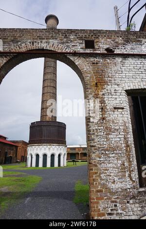 Historischer Ziegelschornstein steht hoch hinter einem verwitterten Bogenweg an einem bewölkten Tag Stockfoto