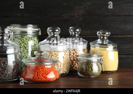 Verschiedene Arten von Hülsenfrüchten und Getreide in Glasgefäßen auf Holztisch. Organische Körner Stockfoto