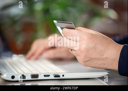Die Hände eines Mannes mittleren Alters geben Kreditkarteninformationen ein Stockfoto