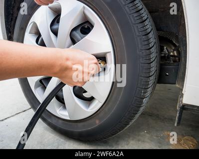 Mann, der Luftdruck in den Autoreifen einfüllt Stockfoto