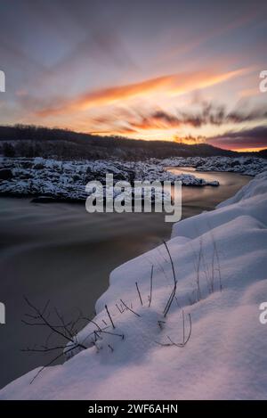 Ein farbenfroher langer Sonnenaufgang an den Great Falls entlang des Potomac River nach einem frischen Schneefall. Stockfoto