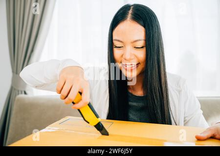 Eine Frau hält einen Universalschneider für präzises Auspacken und enthüllt Online-Shopping-Inhalte Stockfoto