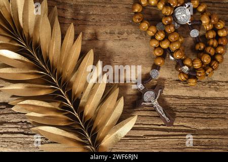 Rosenkranz und goldenes Palmblatt auf Holztisch. Palm Sunday Konzept Stockfoto