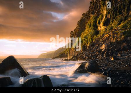 Die Wellen des Ozeans prallen gegen Felsen mit einer majestätischen Bergkulisse. Stockfoto