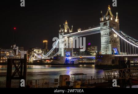 Ein nächtlicher, lang ausgerichteter Blick auf die Tower Bridge von der Nordseite der Themse mit wunderschönen Lichtreflexionen auf dem Wasser. Stockfoto