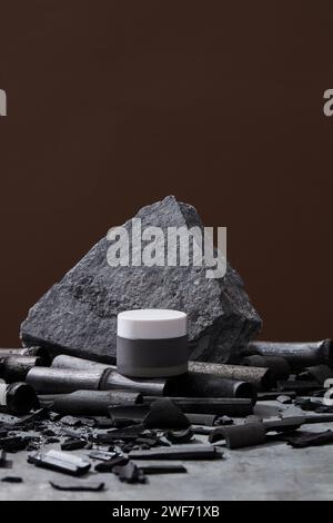 Cremeglas, grauer Stein und Bambuskohle auf dunklem Hintergrund. Stellen Sie den Creme-Behälter nach. Hautpflegekonzept. Bio-Kosmetik, Kosmetikkonzept Stockfoto