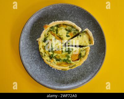 Eine Kürbis-Ricotta-Spinat-Quiche auf einem Teller vor hellem Hintergrund Stockfoto