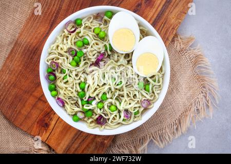 Spinat- und Grünkohl-Ramen-Nudeln mit Frühlingszwiebeln, rustikalem Erbsenholz und Sackleinen-Oberfläche mit Kopierraum Stockfoto