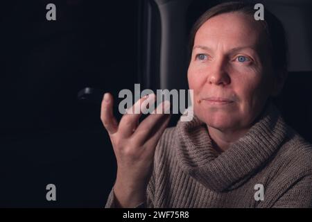 Frau, die auf dem Handy von der Rückbank des Autos auf einem Roadtrip in der Nacht spricht, selektiver Fokus Stockfoto