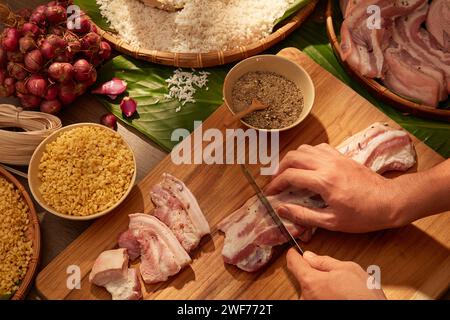 Model Hand schneidet Schweinefleisch als Zutaten für die Zubereitung von klebrigem Reiskuchen (chung-Kuchen). Traditionelles Essen im Tet-Urlaub. Chinesisches Neujahrsfest Stockfoto