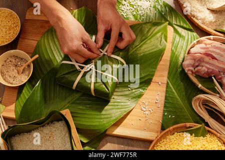 Hände von Person, die traditionelle klebrige Reiskuchen für das chinesische Neujahrsfest herstellen. Alle Zutaten werden auf einen Holztisch gestellt. Draufsicht Stockfoto