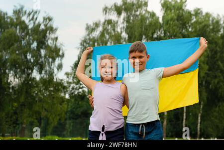 Ukrainische Kinder Junge und Mädchen mit gelber und blauer Flagge der Ukraine im Stadion. Ukrainischer Unabhängigkeitstag. Tag der Verfassung. Flaggensymbole für Großbritannien Stockfoto