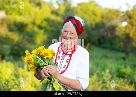 Sonnenblumenstrauß in den Händen einer alten Großmutter in einem gestickten Hemd und roten Perlen. Unabhängigkeitstag der ukraine, Verfassung, fla Stockfoto