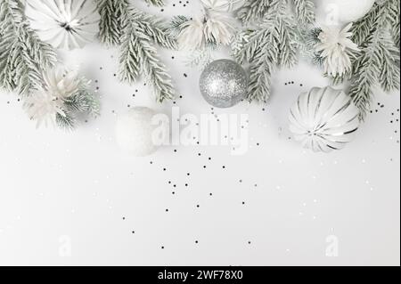 Weihnachtskomposition, weiße und silberne Dekorationen, Tannenzweige, weiße Blumen, silberne Sterne Konfetti auf weißem Hintergrund. Stockfoto