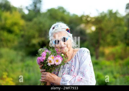 Porträt einer glücklichen Großmutter mit einem Blumenstrauß aus Astern. Begriffe zum Dienstalter Stockfoto